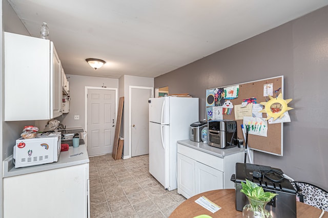 kitchen with light tile patterned floors, white cabinets, and white refrigerator