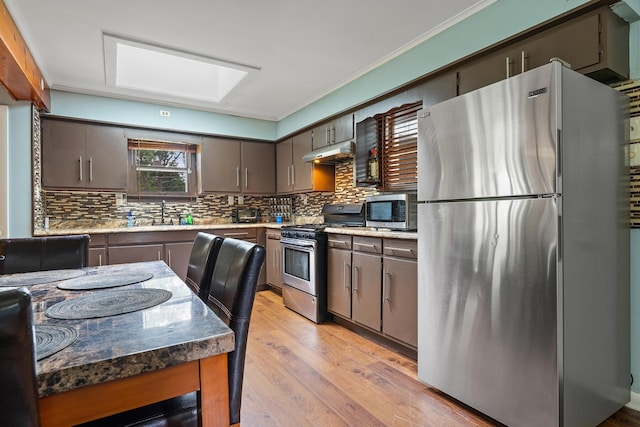 kitchen with light hardwood / wood-style flooring, tasteful backsplash, stainless steel appliances, crown molding, and a skylight