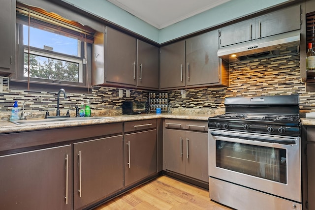 kitchen featuring tasteful backsplash, light wood-type flooring, range with gas cooktop, light stone countertops, and sink