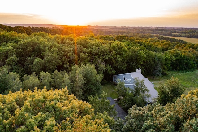 aerial view at dusk featuring a forest view