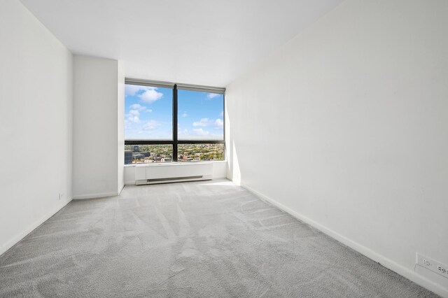 empty room with carpet flooring, baseboards, and baseboard heating