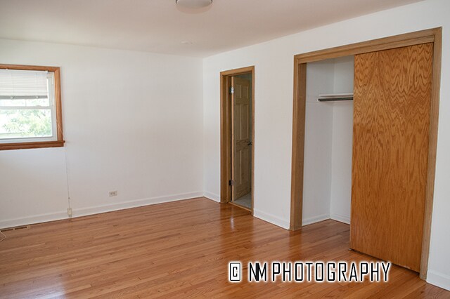 unfurnished bedroom with hardwood / wood-style flooring and a closet