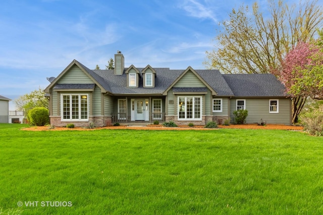 rear view of house with a lawn, stone siding, a chimney, and covered porch