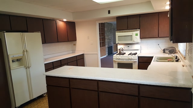 kitchen with dark brown cabinets, decorative backsplash, white appliances, sink, and tile patterned flooring