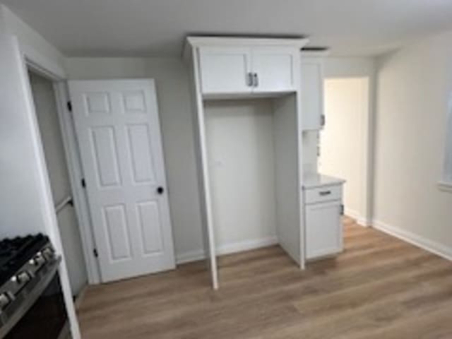 kitchen with range, light hardwood / wood-style flooring, and white cabinetry