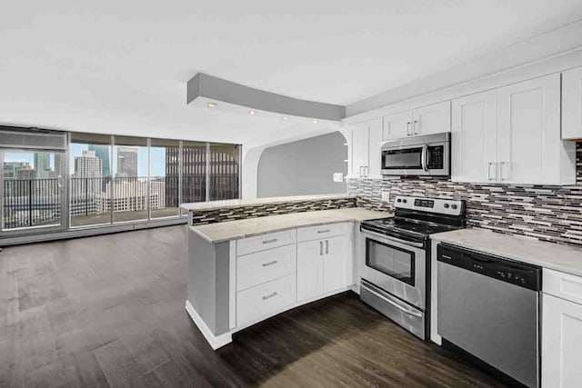 kitchen with dark hardwood / wood-style flooring, white cabinets, dishwasher, stove, and kitchen peninsula