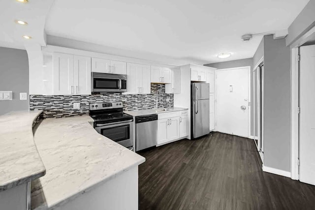 kitchen featuring appliances with stainless steel finishes, tasteful backsplash, white cabinetry, light stone countertops, and dark wood-type flooring