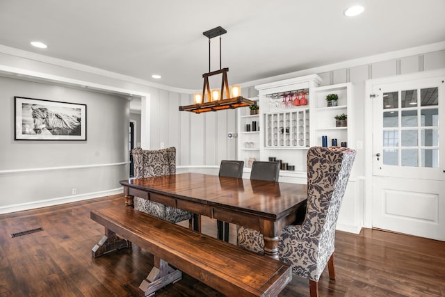 dining space with a chandelier, crown molding, and dark wood-type flooring