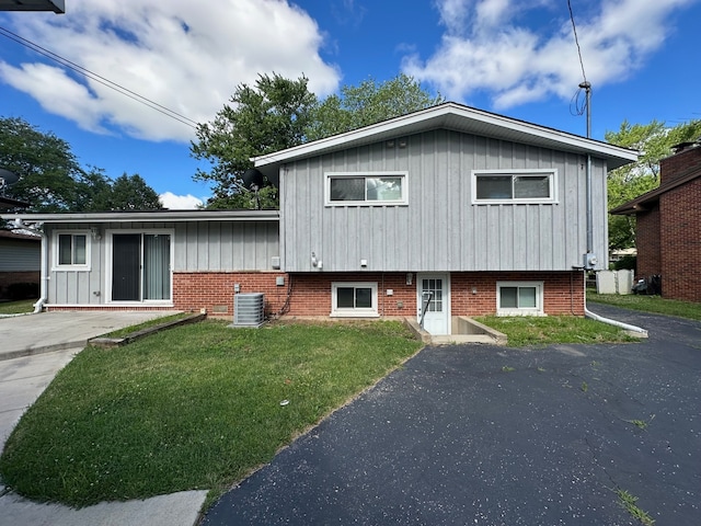 split level home featuring central AC unit and a front yard