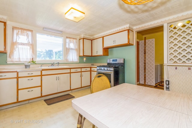 kitchen featuring stainless steel gas range, sink, and cream cabinetry