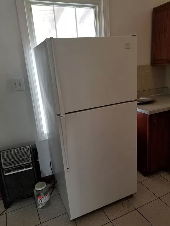 kitchen with light tile patterned flooring, backsplash, white fridge, and plenty of natural light