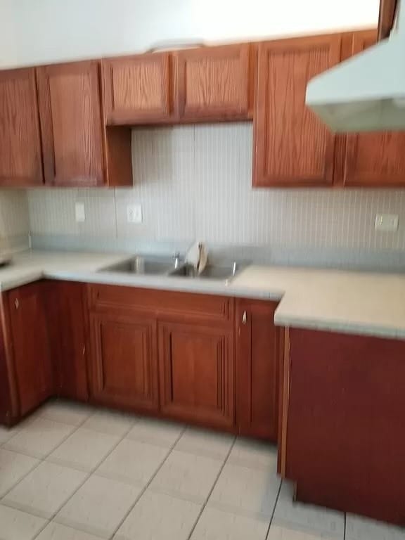 kitchen featuring sink, wall chimney exhaust hood, and light tile patterned floors