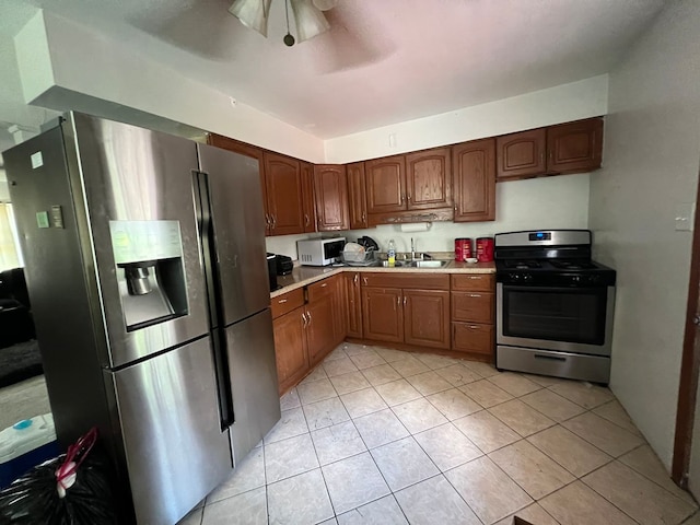 kitchen with appliances with stainless steel finishes, light tile patterned flooring, sink, and ceiling fan