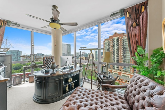 carpeted home office featuring floor to ceiling windows and ceiling fan