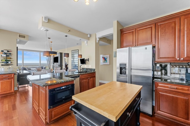 kitchen with wood-type flooring, appliances with stainless steel finishes, hanging light fixtures, and a kitchen island