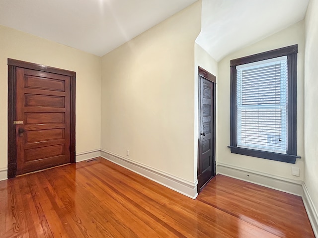 empty room featuring vaulted ceiling and wood-type flooring