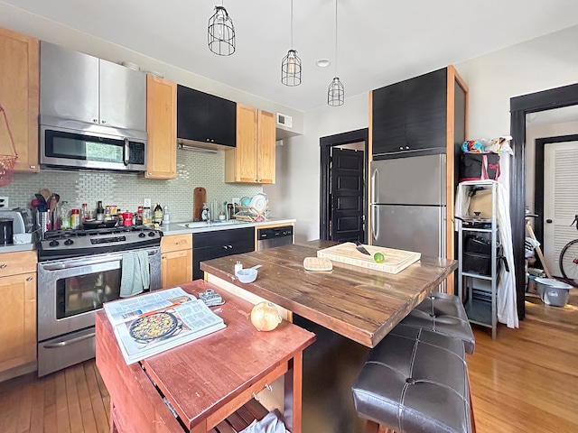 kitchen with stainless steel appliances, a center island, light hardwood / wood-style floors, and backsplash