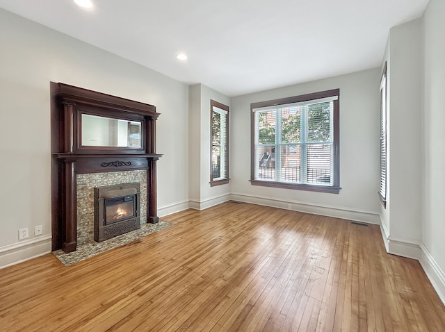 unfurnished living room featuring light wood-type flooring and a stone fireplace