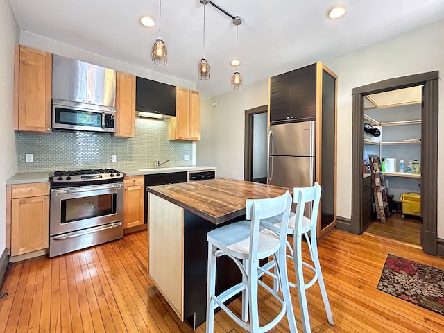 kitchen featuring stainless steel appliances, butcher block countertops, hanging light fixtures, light hardwood / wood-style floors, and tasteful backsplash