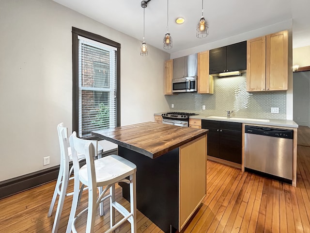 kitchen with pendant lighting, appliances with stainless steel finishes, wooden counters, decorative backsplash, and a kitchen island