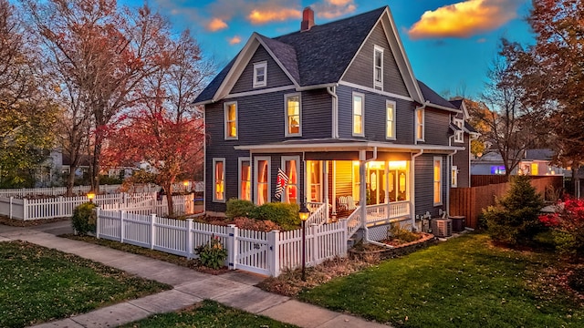 back house at dusk featuring a lawn, central air condition unit, and a porch