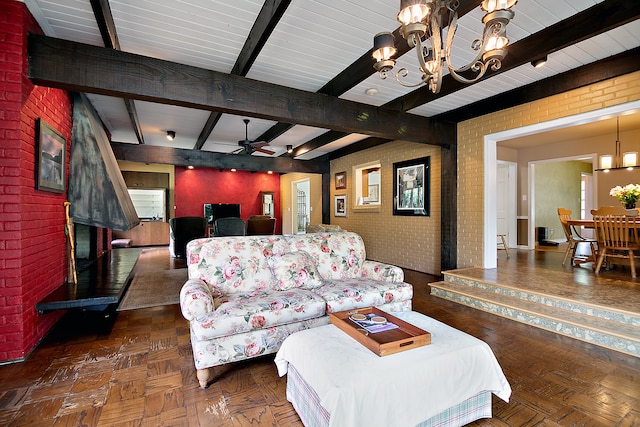 living room with dark parquet flooring, ceiling fan with notable chandelier, beam ceiling, and brick wall