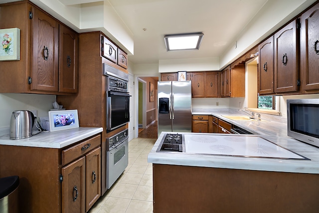 kitchen with stainless steel appliances, light tile patterned flooring, and sink