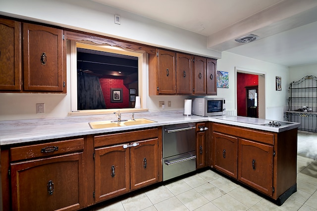 kitchen with cooktop, light tile patterned floors, kitchen peninsula, and sink