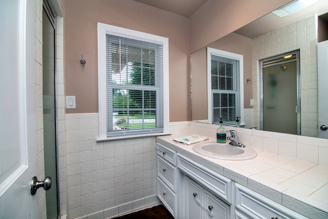 bathroom with vanity, an enclosed shower, and tile walls