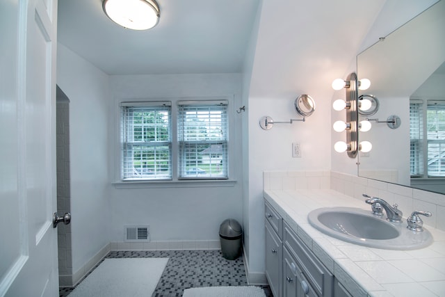 bathroom with tile patterned flooring, vaulted ceiling, and vanity