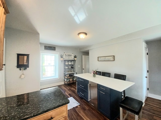 kitchen featuring a breakfast bar area, dark wood-type flooring, and a kitchen island