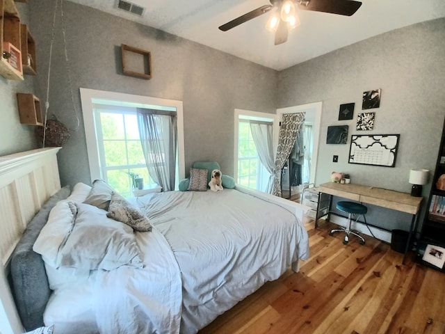 bedroom featuring built in desk, ceiling fan, and hardwood / wood-style floors