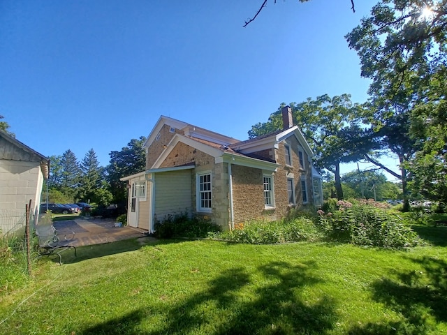 view of side of property with a patio and a yard