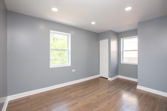 unfurnished bedroom featuring baseboards, wood finished floors, recessed lighting, and a closet