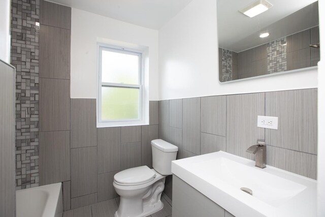 full bathroom with tile walls, toilet, wainscoting, vanity, and shower / bathtub combination