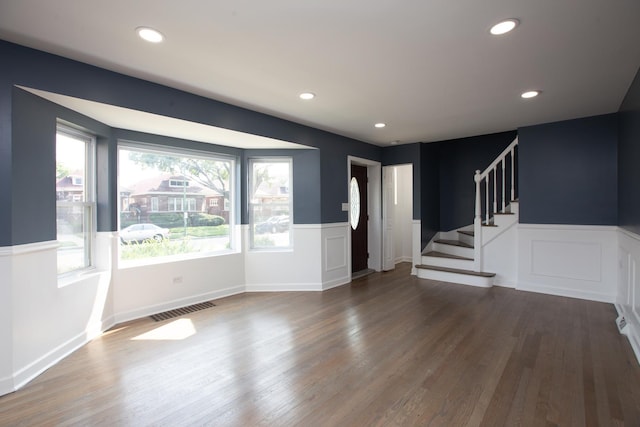 foyer entrance with wainscoting, stairway, dark wood finished floors, recessed lighting, and a decorative wall