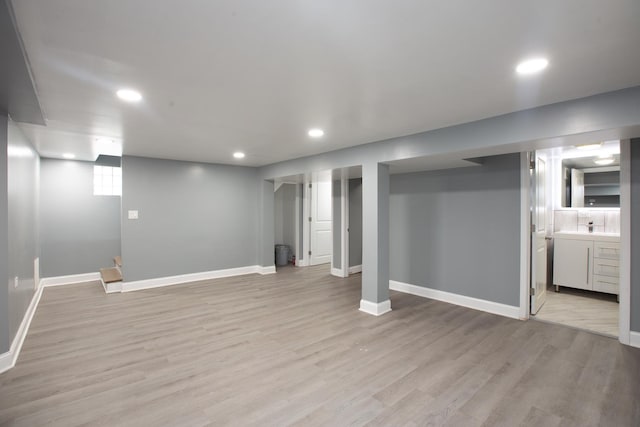 below grade area with recessed lighting, light wood-style flooring, and baseboards