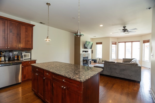 kitchen featuring dark stone counters, dark hardwood / wood-style flooring, a fireplace, stainless steel dishwasher, and ceiling fan