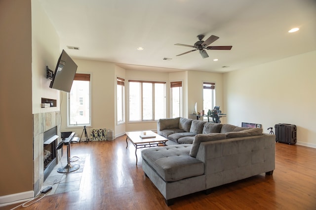 living room featuring hardwood / wood-style flooring, a tile fireplace, and ceiling fan