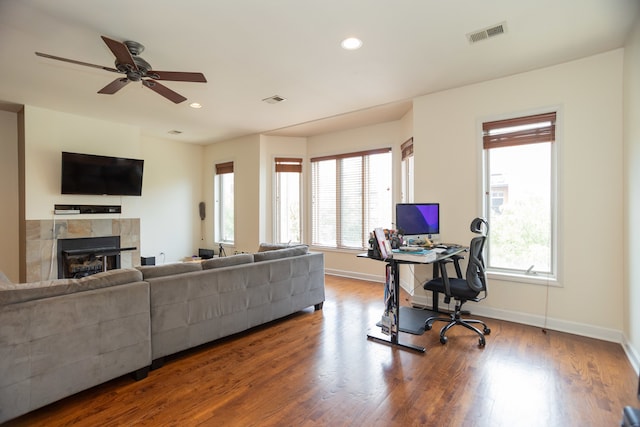 living room featuring a wealth of natural light, a fireplace, dark hardwood / wood-style floors, and ceiling fan