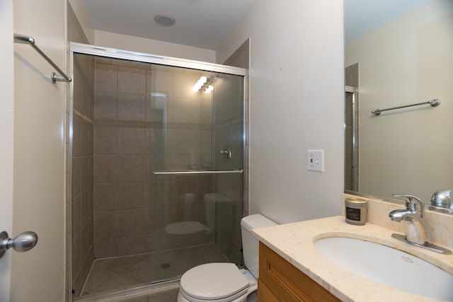 bathroom featuring toilet, vanity, and a shower with shower door