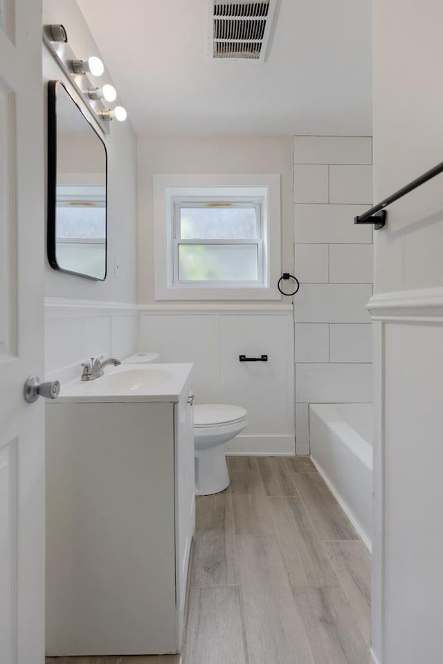 bathroom with vanity, wood-type flooring, a wealth of natural light, and toilet