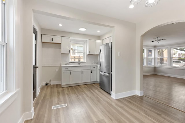 kitchen with white cabinetry, sink, stainless steel fridge, and light wood-type flooring