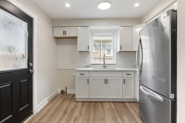 kitchen featuring stainless steel refrigerator, sink, light hardwood / wood-style flooring, and white cabinets