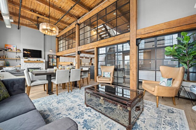 living room featuring a brick fireplace, wooden ceiling, hardwood / wood-style floors, beam ceiling, and a towering ceiling