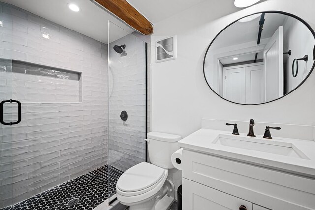 bathroom featuring vanity, a shower with shower door, and toilet