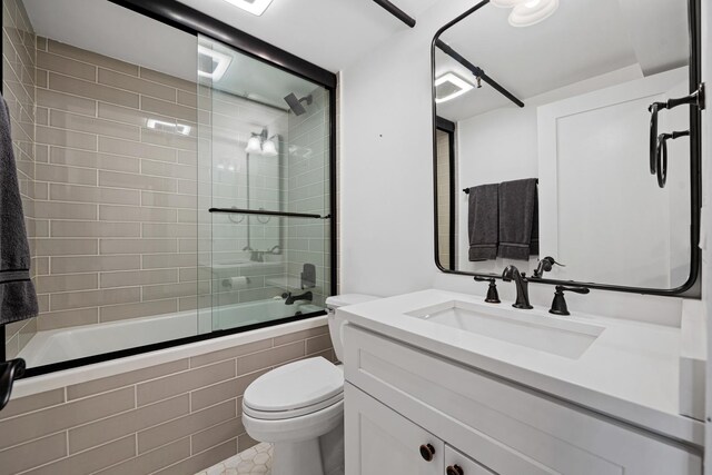 full bathroom with tile patterned floors, shower / bath combination with glass door, toilet, and vanity