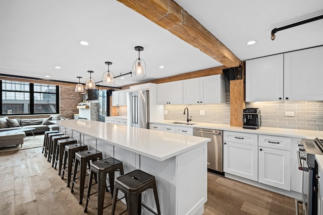 kitchen featuring a kitchen island, decorative light fixtures, light hardwood / wood-style flooring, appliances with stainless steel finishes, and sink