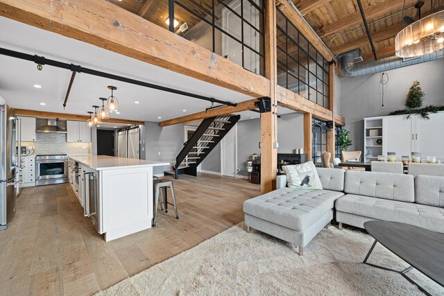 living room featuring light wood-type flooring, beam ceiling, and a high ceiling