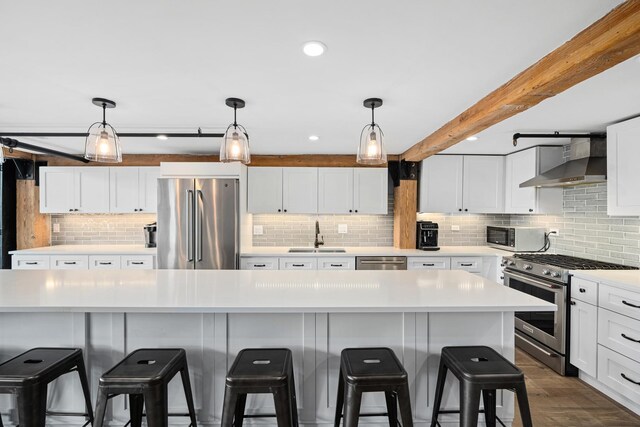 kitchen featuring tasteful backsplash, decorative light fixtures, appliances with stainless steel finishes, and wall chimney exhaust hood